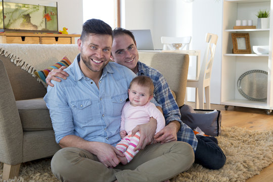 Same sex male couple posing with their daughter in their home