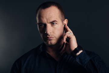 Security detail, bodyguard holding earpiece. Studio shot.