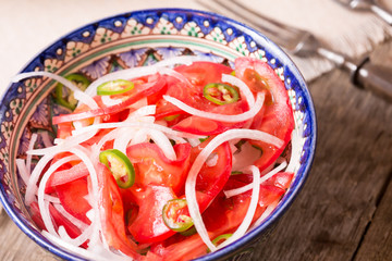 Pilaf and achichuk salad in handmade plate on wooden background