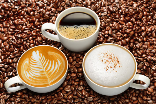 Variety of cups of coffee on coffee beans background