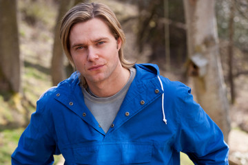 Attractive young man sitting outside. He is looking pensively at the camera.