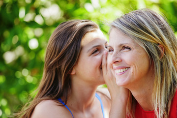 Teen whispering in the ear of her mother