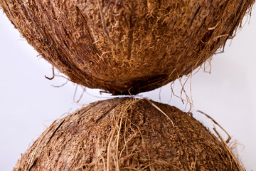 Whole coconuts facing each other symmetrically shot from above on a white background