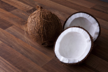 Coconuts whole and halved shot on a wooden background at an angle