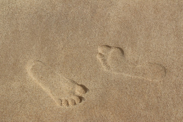 Fototapeta na wymiar Two different footprints in the sand, with normal and flat foot arch 