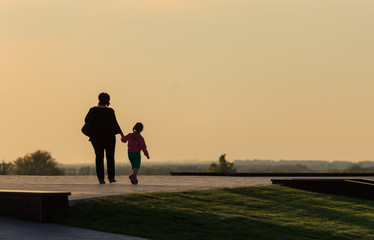 silhouettes of mother and daughter strolling at sunset