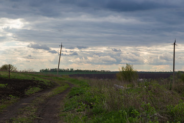 Fototapeta na wymiar curving rural road on the background of gloomy sunset clouds