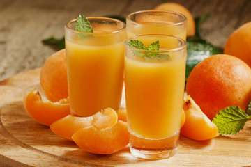 Fresh apricot juice and apricots with mint on wooden board, sele