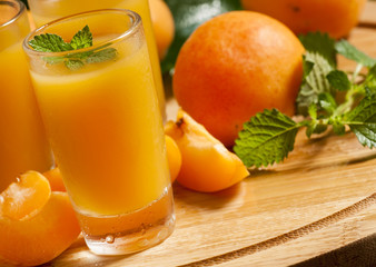 Fresh apricot juice and apricots with mint on wooden board, sele