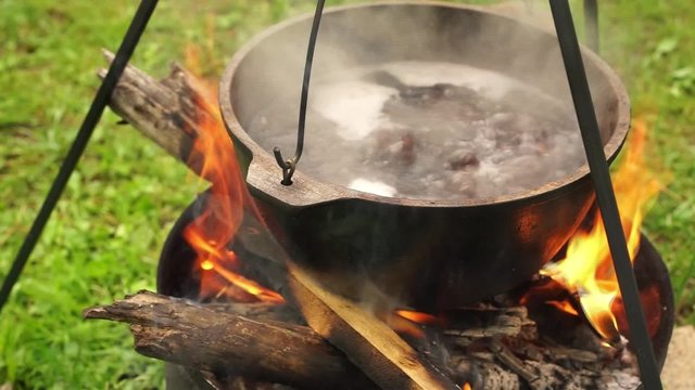 Cooking soup in metal pan on campfire