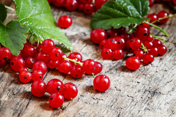 Red currants with leaves on old wooden background, selective foc