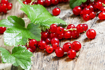 Red currants with leaves on old wooden background, selective foc