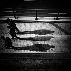 silhouette of three men walking down street