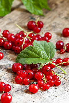 Red currants with leaves on old wooden background, selective foc