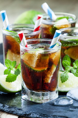 Cuba Libre with lime, mint and ice in a glass, selective focus