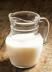 Jug of milk on old wooden table in rustic style, selective focus