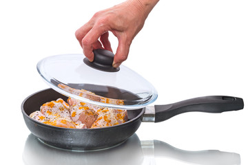 Chicken legs in a frying pan with glass lid