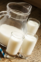 Jug of milk on old wooden table in rustic style, selective focus