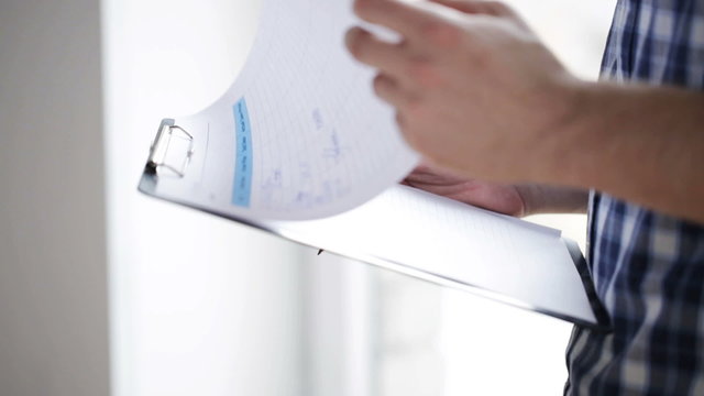 close up of man looking and writing to clipboard