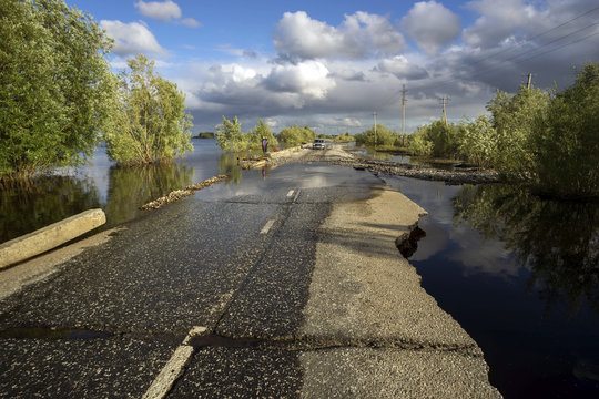  flooded section of road with broken asphalt