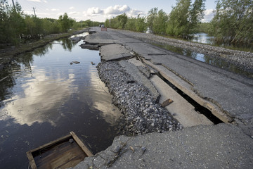 The consequences of the flood washed  road with sagging plates