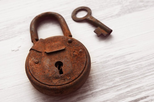 Old rusty lock and key on a wooden light background
