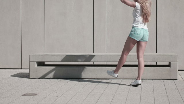 Energetic Young Woman in Fitness Outfit, Exercising Using Jumping Rope Against White Wall Background on a Sunny Climate.
