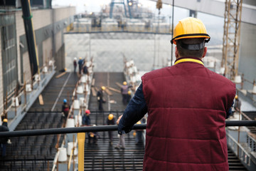 Engineer supervising workers from platform