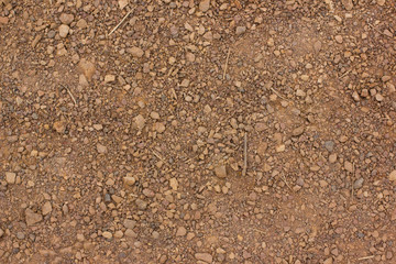 Texture of dry red clay with stones close-up.
