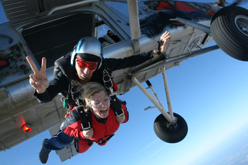 Instructor skydiving jump from the plane and his student shouts. - obrazy, fototapety, plakaty