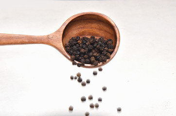 Black pepper spices in wooden spoon