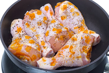 Raw chicken legs in a frying pan