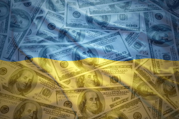 colorful waving ukrainian flag on a american dollar money background © luzitanija