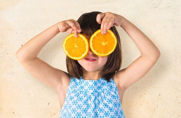 Girl holding orange slices as glasses