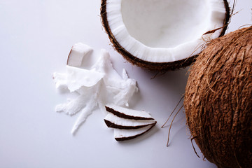Whole and halved coconuts shot from above on a white backgroundfrom above