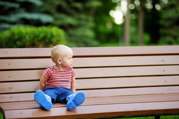 Toddler boy sitting on a bench