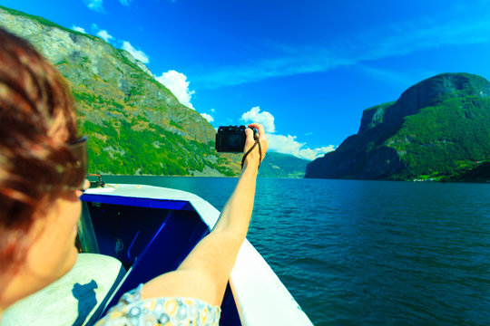 Tourism. Woman with camera on ship, fjord in Norway.