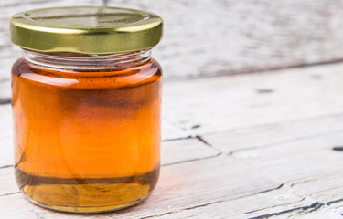 Honey in a mason jar over rustic weathered wooden background