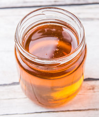Honey in a mason jar over rustic weathered wooden background