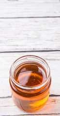 Honey in a mason jar over rustic weathered wooden background