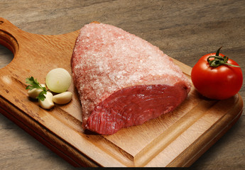 Raw meat selection on wooden cutting board with knife