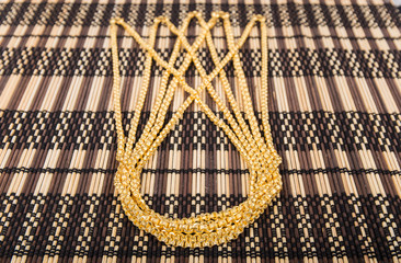 golden necklace on bamboo mat