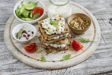rye biscuit with cheese, cucumber and cilantro on a light wooden background - healthy snack