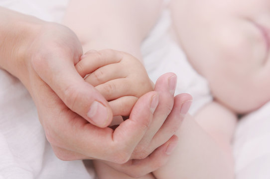 close up mother's hand holding little hand of her baby