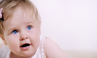 portrait of cute interested baby girl with big blue eyes