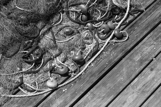Fishing net laying on wooden pier, black and white
