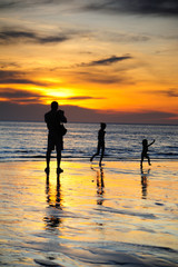 Silhouette of two adults and a child at the coast