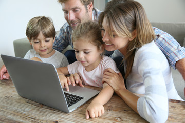Parents with kids at home using laptop computer