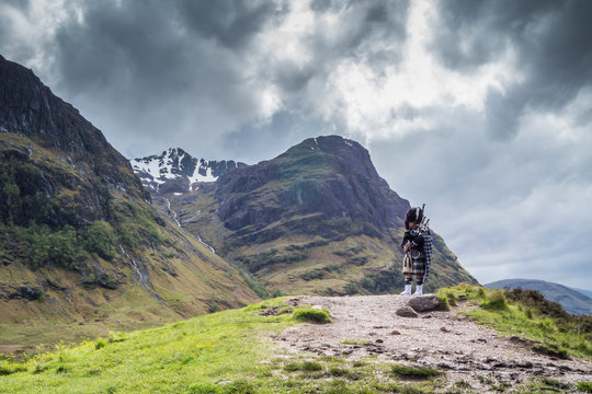 Traditional scottish bagpiper in full dress code in the highlands