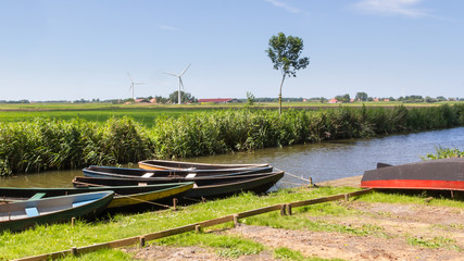 Typical Dutch landscape with wooden rowing boats and modern wind